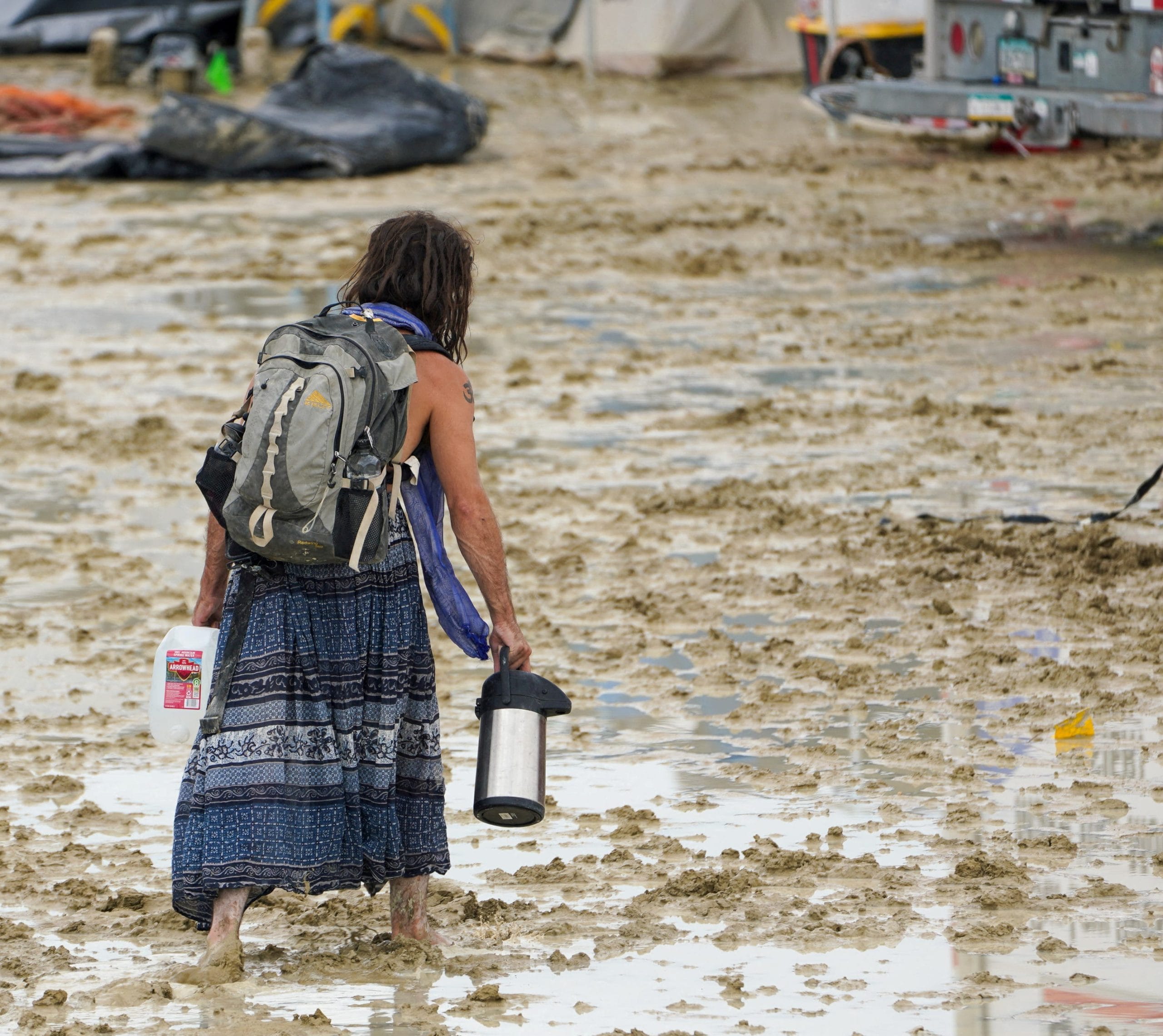 A Burning Man participant makes their way through the mud in Black Rock City, in the Nevada desert, after a rainstorm | Trevor Hughes/USA Today Network Via Reuters