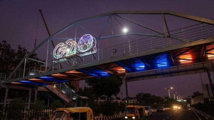 Traffic moves past under a G20 logo installed on a pedestrian bridge in front of the main venue of the summit in New Delhi, India | Reuters