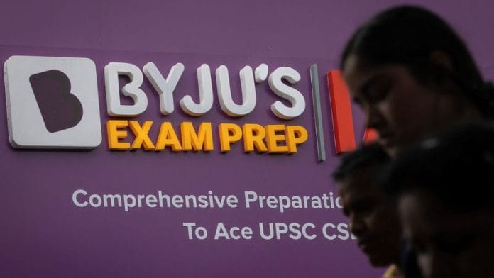 People walk past an advertising hoarding of Byju's outside its branch in New Delhi | Reuters