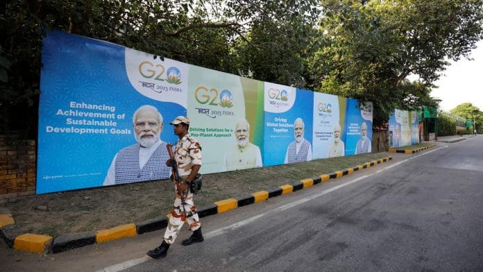 A security force personnel patrols past hoardings featuring PM Narendra Modi along an empty road ahead of the G20 Summit in New Delhi, on 8 September 2023 | Reuters