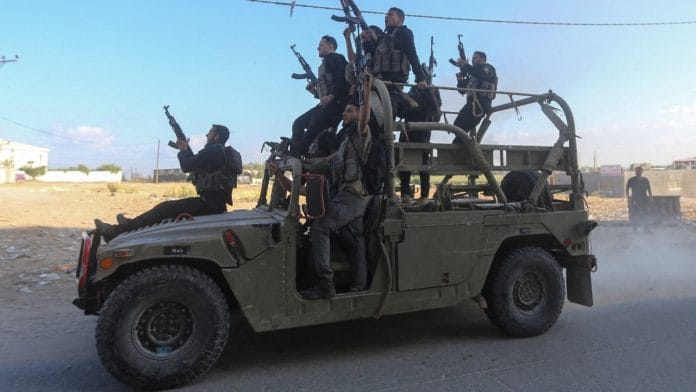 Palestinian militants ride an Israeli military vehicle that was seized by gunmen who infiltrated areas of southern Israel, in the northern Gaza Strip | Reuters