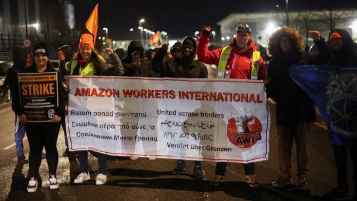 People hold a banner during a Black Friday strike outside the Amazon warehouse, in Coventry, Britain November 24, 2023 | Reuters