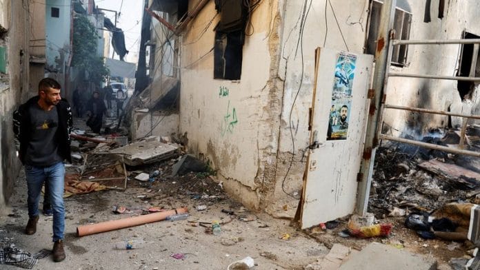 A Palestinian checks the damage in a street in the aftermath of an Israeli raid in Jenin, in the Israeli-occupied West Bank, November 26, 2023. REUTERS