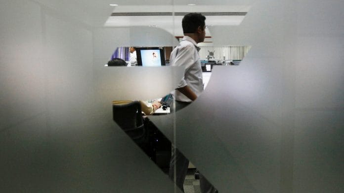A currency trader is pictured through the symbol for the Indian Rupee on the floor of a trading firm in Mumbai | Reuters file photo