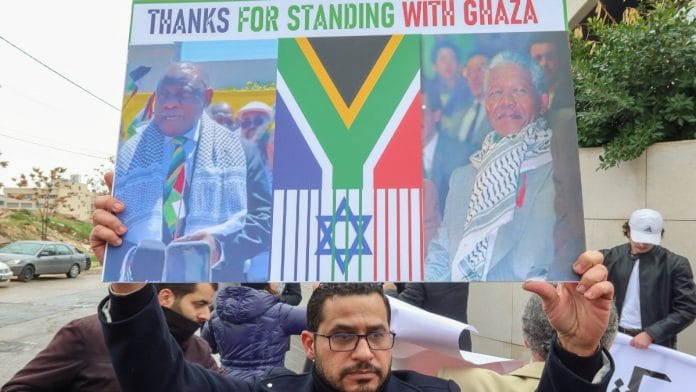 A demonstrator holds a sign during a protest as judges at The International Court of Justice (ICJ) in the Hague, hear a request for emergency measures to order Israel to stop its military actions in Gaza, in Amman Jordan on 11 January | Credit: Reuters/Jehad Shelbak