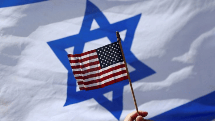 FILE PHOTO: A view of a U.S. flag and an Israeli flag held up by people during a demonstration to show support for U.S. President Joe Biden, for not inviting Israeli Prime Minister Benjamin Netanyahu to the White House, in front of the U.S. Consulate in Tel Aviv, Israel, March 30, 2023 | File Photo | Ronen Zvulun | Reuters