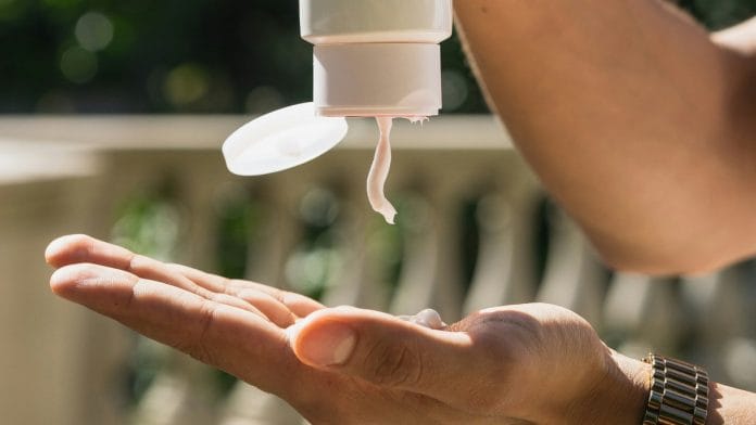 a person pours a cream on their hand, representing a skincare product being used.