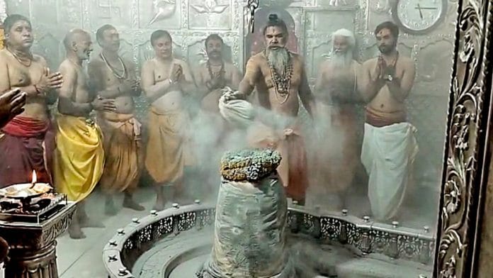 A priest performs abhishek on Shiva Linga during the 'Phoolon Wali Holi' celebrations at Mahakaleshwar Temple, in Ujjain on Sunday, 24 March 2024 | ANI