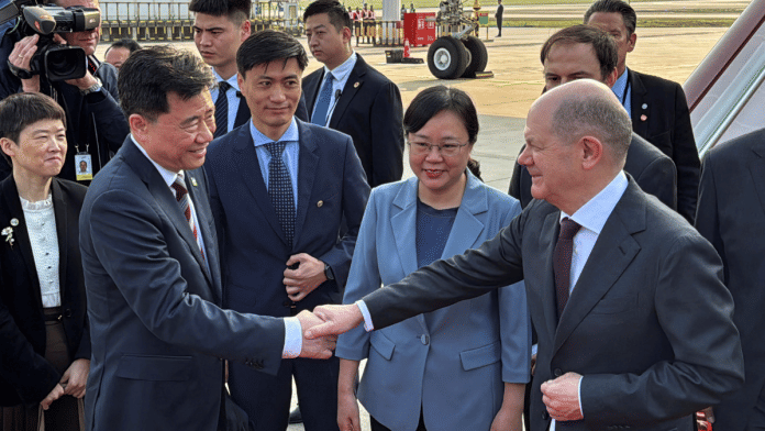 German Chancellor Olaf Scholz shakes hands with Chinese Ambassador to Germany Wu Ken next to Chongqing Vice Mayor Zhang Guozhi, upon arriving at the airport in Chongqing, China | Reuters/Andreas Rinke