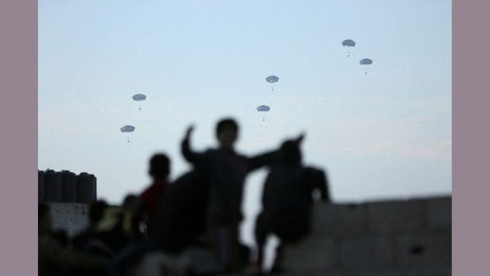 People watch as U.S. military carries out its first aid drop over Gaza | Reuters
