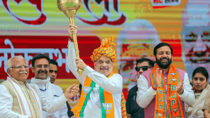 Union Home Minister Amit Shah holds a mace during a public meeting in Karnal. Haryana Chief Minister Nayab Singh Saini and former CM Manohar Lal Khattar also pictured | ANI