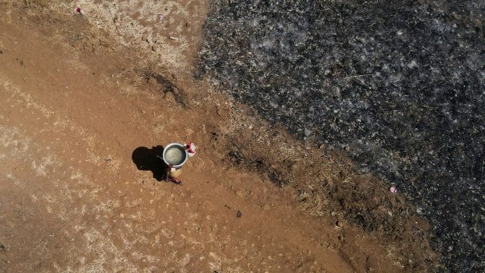 A drone view of a woman carrying a utensil filled with water after drawing it from a well on a hot day in Kasara, India, May 1, 2024. REUTERS/Francis Mascarenhas/File Photo