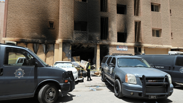 A Kuwaiti police officer is seen in front of a burnt building following a deadly fire, in Mangaf, southern Kuwait, 12 June, 2024. REUTERS/Stringer