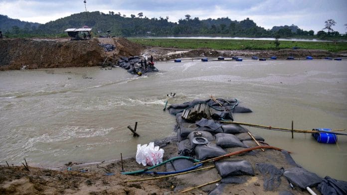 Workers use geo-bags to restore an embankment that was damaged by flood water, at Hatimura in Nagaon district, Friday/ PTI Photo