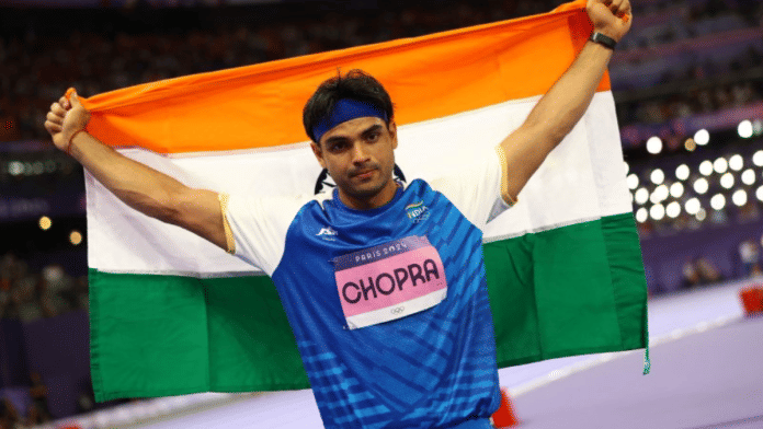 Paris 2024 Olympics - Athletics - Men's Javelin Throw Final - Stade de France, Saint-Denis, France - 08 August, 2024. Neeraj Chopra of India celebrates with his national flag after winning silver Reuters/Kai Pfaffenbach