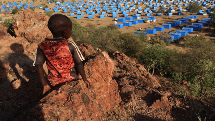 A boy sits atop a hill overlooking a refugee camp near the Chad-Sudan border, 9 November, 2023 | Reuters/El Tayeb Siddig/File Photo