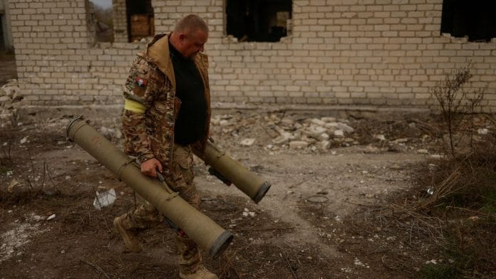 A Ukrainian serviceman carries captured anti-tank grenade launchers at a former position of Russian soldiers in the village of Blahodatne in Kherson region, Ukraine | REUTERS/Valentyn Ogirenko/File Photo