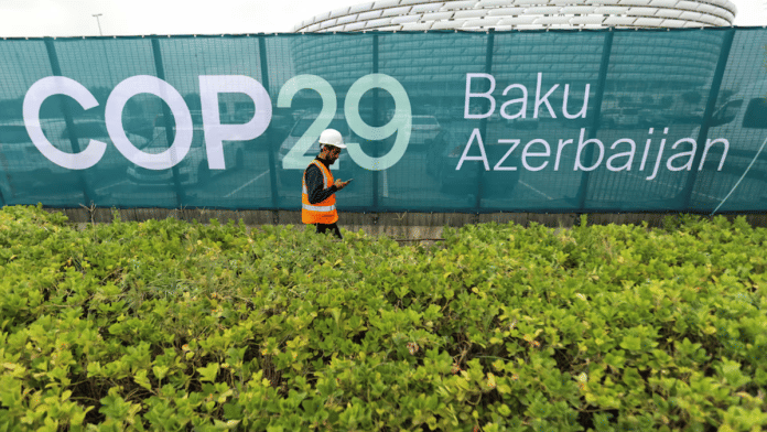 A worker walks along a fence near the Baku Olympic Stadium, the venue of the COP29 United Nations Climate Change Conference, in Baku, Azerbaijan, 18 October 2024 | Aziz Karimov | Reuters