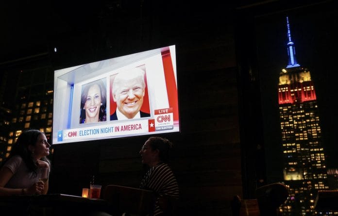 People attend a watch party at 230 Fifth Rooftop Bar, as the Empire State Building is seen in the background, in New York City, U.S. | Andrew Kelly | Reuters