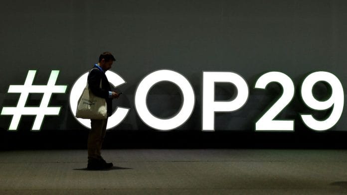 A man stands next to a COP29 sign in Baku, Azerbaijan. | Reuters