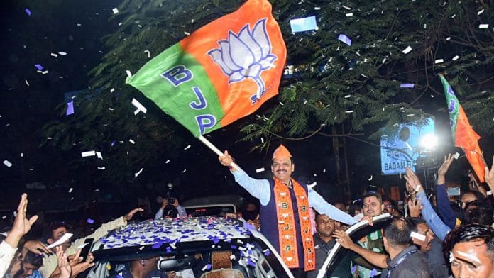 BJP’s Devendra Fadnavis waves the party's flag as he arrives to collect his winning certificate after the Maharastra Assembly election results | ANI