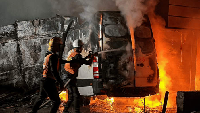Civil Defense members put out a fire in a broadcast van following an Israeli strike that killed five journalists of Al-Quds Al-Youm television channel, according to medics with the Gaza health authorities, in the vicinity of Al-Awda hospital in Nuseirat in central Gaza on 26 December 2024. | Khamis Said | Reuters