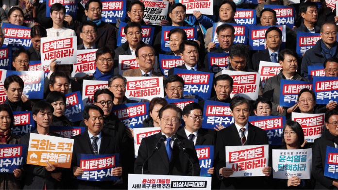 South Korea's main opposition Democratic Party leader Lee Jae-myung looks on as people hold placards that read 