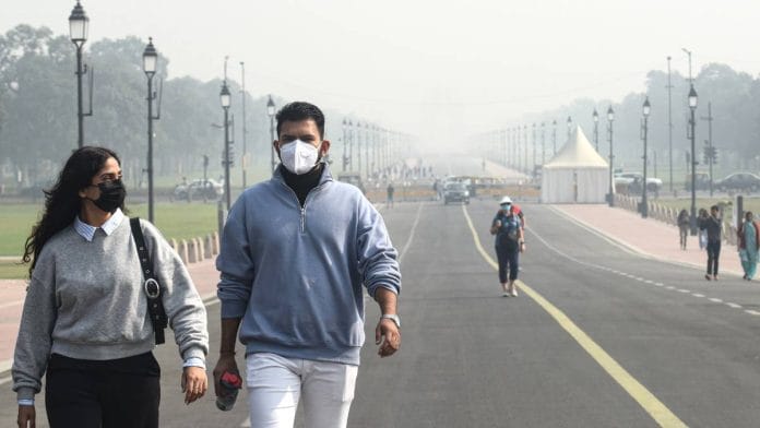 People wearing masks walk at Kartavya Path amid the smog in New Delhi | Photo: ANI