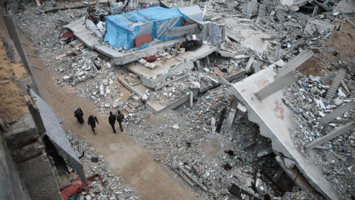 Palestinians walk past the rubble of houses destroyed in previous Israeli strikes, ahead of a ceasefire set to take effect on Sunday, in Khan Younis in the southern Gaza Strip on 16 January 2025. | Hatem Khaled | Reuters