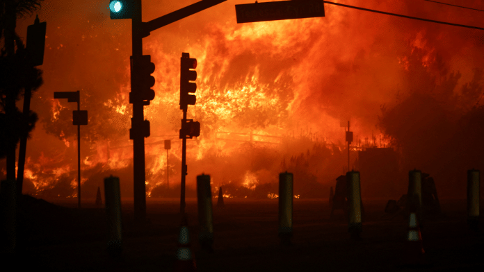 A signal light goes green on the Pacific Coast Highway as a wildfire burns in the Pacific Palisades neighborhood of west Los Angeles, California Tuesday | Reuters/Daniel Cole
