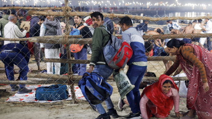 A woman crawls under a fence, after a deadly stampede before the second 