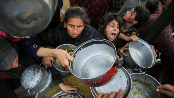 Palestinians gather to receive food cooked by a charity kitchen, before a ceasefire between Hamas and Israel takes effect, in Khan Younis, in the southern Gaza Strip | Reuters/Hatem Khaled