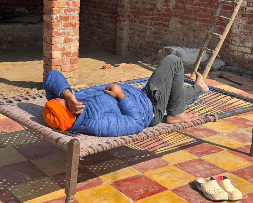 Daler Singh, who filed a complaint against his agent Satnam, rests on a cot in the courtyard of his house in Amritsar's Salempura village.