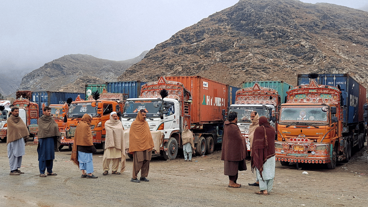 File photo of people standing next to parked trucks loaded with supplies at the Torkham border crossing following the closure of the border crossing between Pakistan and Afghanistan | Reuters
