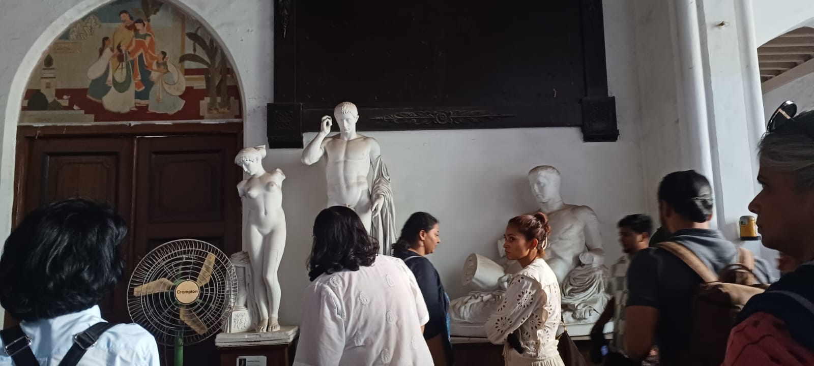 Participants of the heritage walk at a hall in the School with Greek-style sculptures.