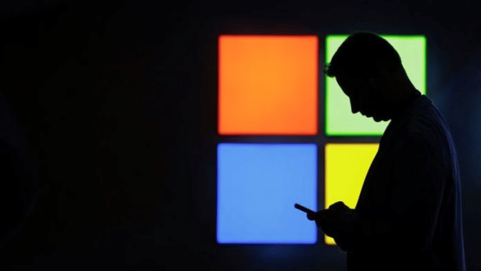 Representational Image | A man against the silhouette of the Microsoft logo | Reuters