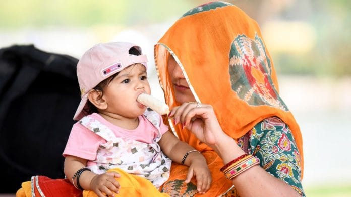 A mother feeds her child ice cream to provide them relief from Delhi's scorching heat | ANI