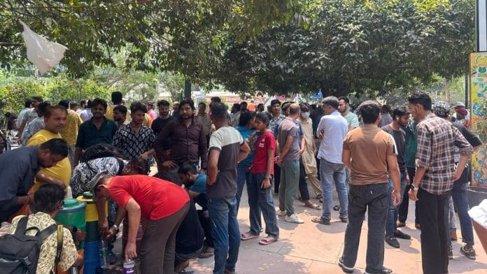 Shopkeepers stand outside the sealed off compound of Dilli Haat, Thursday. | Zenaira Bakhsh | ThePrint