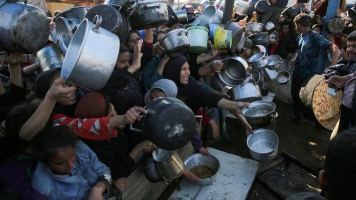 Palestinians gather to receive food cooked by a charity kitchen, amid a hunger crisis, as the Israel-Hamas conflict continues, in Khan Younis in the southern Gaza Strip, on 2 January 2025. | File Photo | Hatem Khaled | Reuters