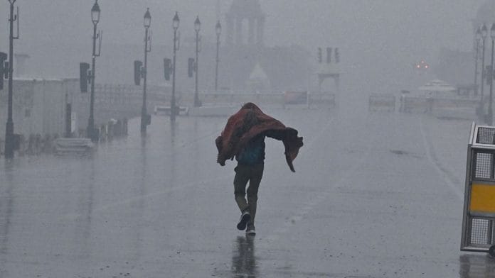 A man covers himself amid heavy rainfall, in New Delhi on 23 May. | ANI