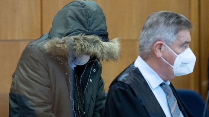 Syrian doctor known as M. by German media sits with his head covered, accompanied by one of his lawyers Ulrich Endres, as he goes on trial in Frankfurt, Germany, on 19 January 2022. | File Photo | Boris Roessler | Pool via Reuters