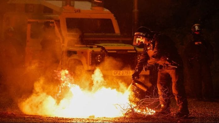A riot police officer tries to extinguish a fire during the 4th night of unrest following a protest in Portadown, Northern Ireland, on 12 June 2025. | Clodagh Kilcoyne | Reuters