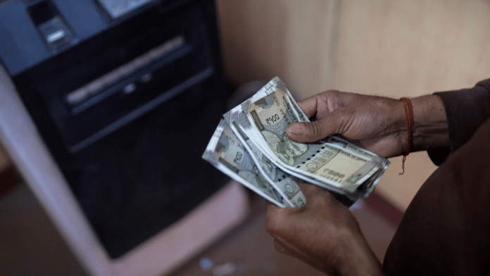 A man counts money after withdrawing it from an automated teller machine (ATM) in New Delhi, India | Representational image | Reuters