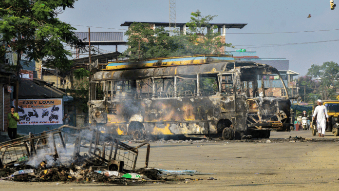 Charred remains of a bus used for transporting central forces after arrest of Meitei leader, in Imphal East district, Manipur, 8 June 2025. | PTI