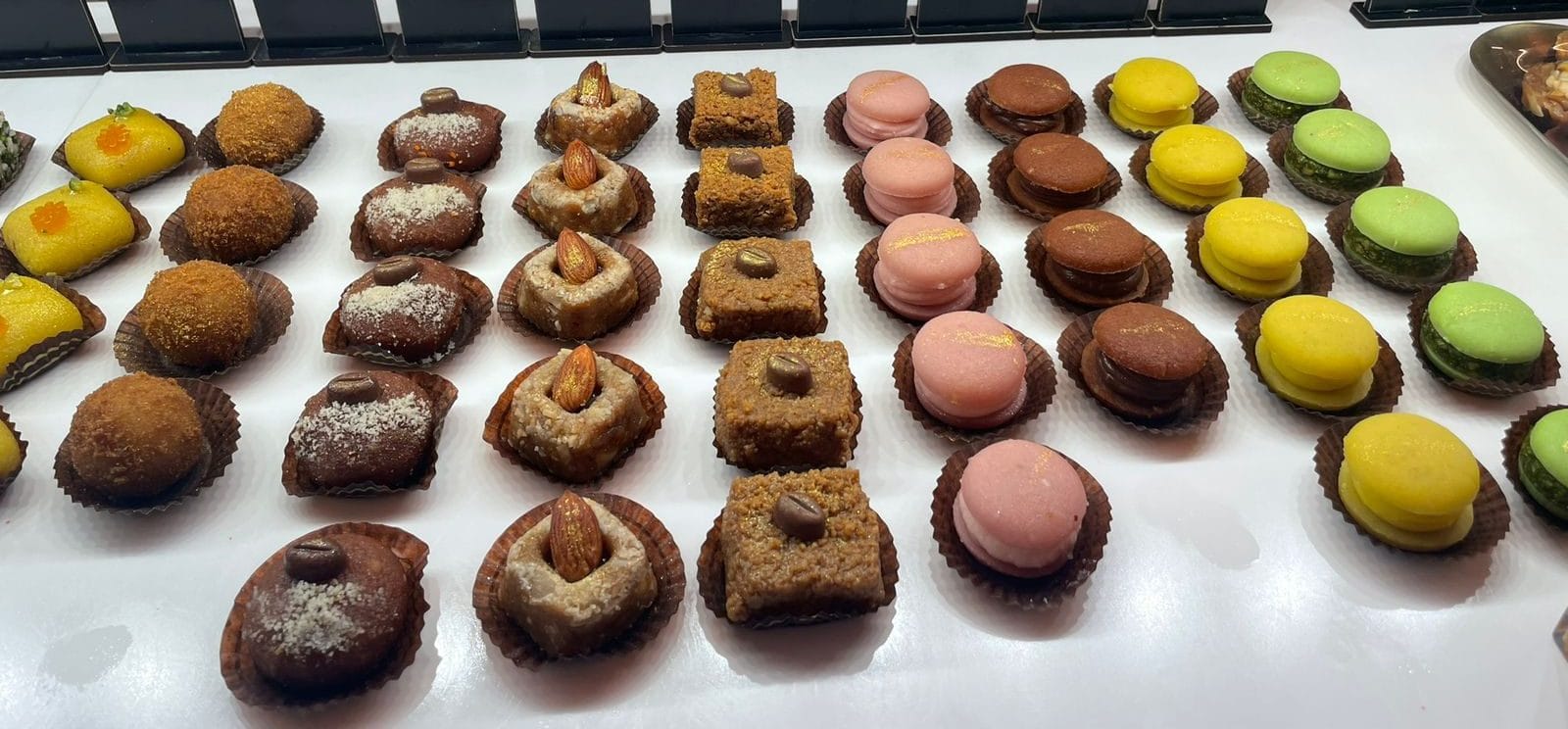 Display of handcrafted sweets at Wishes by Om, including pistachio, rose, and coconut ladoos.