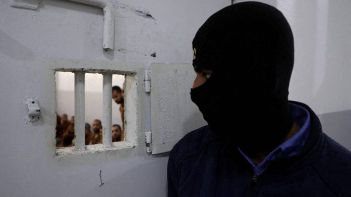 A guard looks at Islamic State fighters in a prison in Syria | Photo: Reuters