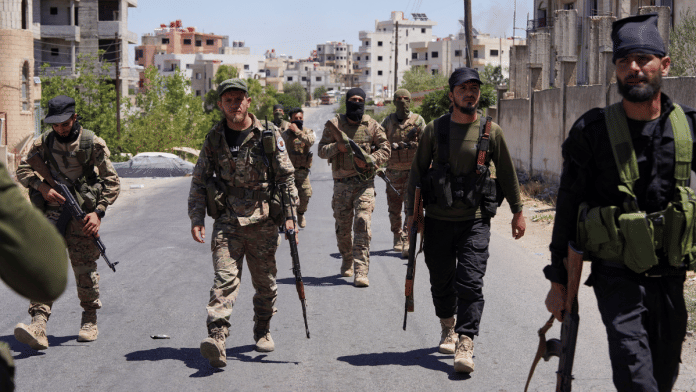Syrian security forces walk together along a street, after clashes between Syrian government troops and local Druze fighters resumed in the southern Druze city of Sweida early on Wednesday | Reuters