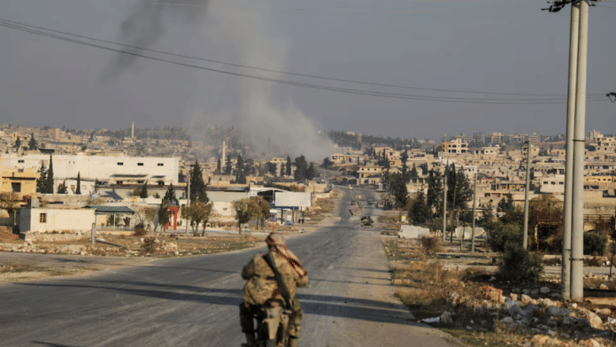 Smoke rises as a member of the rebels led by the Islamist militant group Hayat Tahrir al-Sham drives on a motorbike in al-Rashideen, Aleppo province, Syria November 29, 2024 | Reuters
