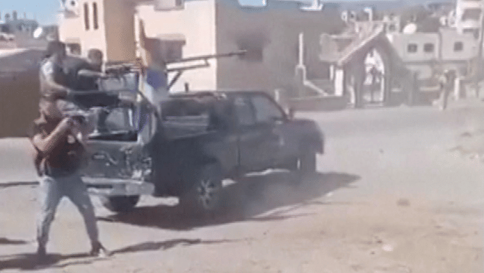 People on the back of a truck with a Druze flag and a man standing with a weapon nearby fire off rounds following clashes between local military groups and tribes in Syria's predominantly Druze city of Sweida, in this still image from an eyewitness video released on July 13, 2025 and obtained from social media | Reuters