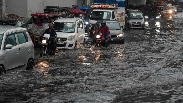 Commuters wade through a waterlogged road following rainfall, in New Delhi, Tuesday, July 29, 2025 | PTI